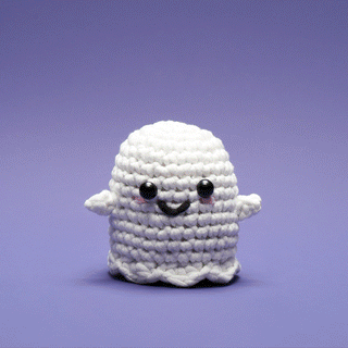 Cute white crocheted ghost amigurumi with black bead eyes and smile on purple background