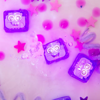 Three purple Glo Pals Snow Pal light-up cubes floating in water with pink stars and beads