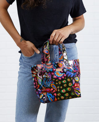 Model holding Consuela Grab N Go Mini tote bag in vibrant multicolor Sophie print pattern.