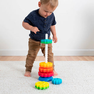 Toddler boy playing with Fat Brain Toys SpinAgain colorful stacking gear toy on white carpet
