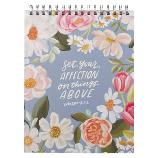Spiral-bound notepad with floral design and Colossians 3:2 scripture verse on blue background