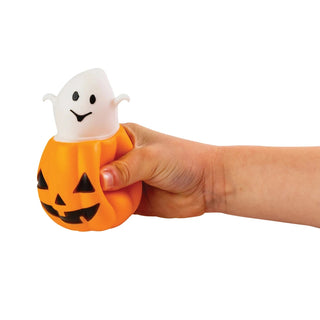 Hand holding orange pumpkin squeeze toy with white ghost popping out