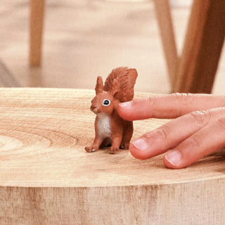 Schleich red squirrel miniature figurine held by hand on wooden surface