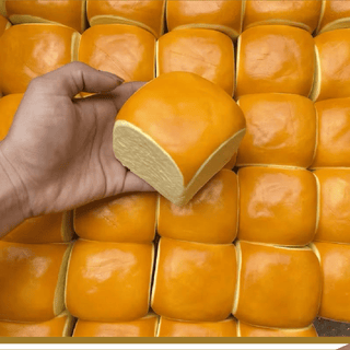 Hand holding a loaf of bread among more loaves on a grid pattern