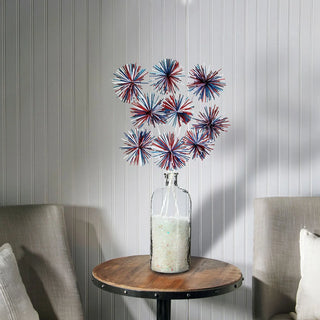 Decorative vase with colorful star-shaped objects on a wooden table against a striped wall.