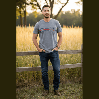 Men's tailored athletic fit heather gray crewneck tee with Americana flag stripe graphic, shown on model in sunlit grassy field