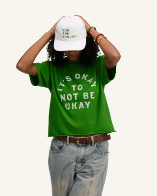 White canvas cap with green 'You Are Enough' text, worn by model