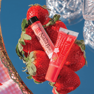 Naked Bee Strawberry Lip Glaze and Lip Gloss duo displayed on fresh strawberries