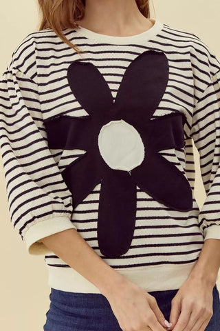 Cream and black striped knit top with large dark floral appliqué patch