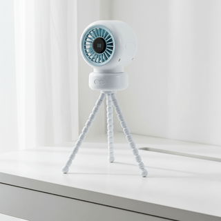 Stroller fan standing on tripod base on a modern white desk with soft natural light