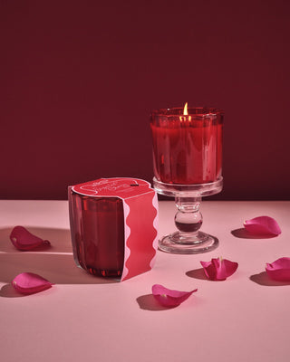 Aromatique Sugared Cherry ribbed red candle in glass vessel on pedestal with packaging and rose petals