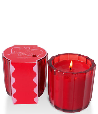 Aromatique Sugared Cherry 8oz red ribbed glass candle lit beside its decorative gift box packaging