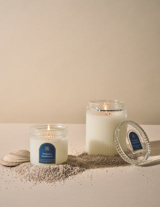Aromatique Sunkissed Sandalwood candles in textured glass jars styled with sand and seashell