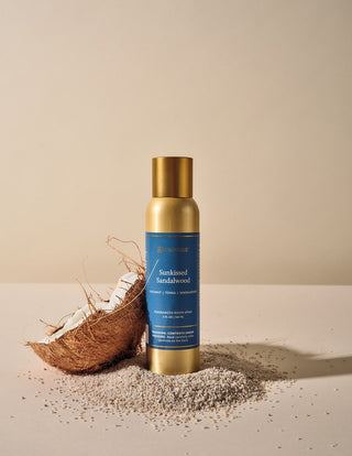 Aromatique Sunkissed Sandalwood gold aerosol room spray styled with coconut and sand