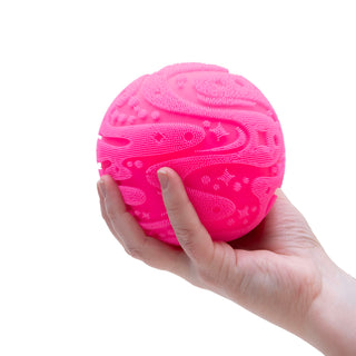 Hand holding a hot pink textured silicone Super Fuzz Ball Needoh stress ball with raised pattern details.