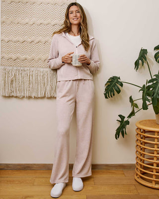 Woman in pink heather wide leg pants and matching zip hoodie holding a mug indoors.