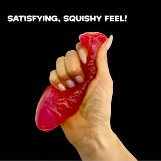 Hand squeezing red Swedish Fish-shaped squishy stress toy against black background