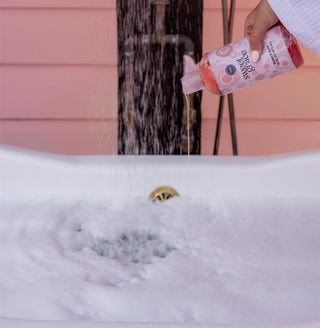 Sweet Grace bubble bath poured into white tub with running water and forming bubbles
