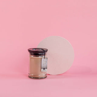 Bridgewater Sweet Grace small jar candle with dark lid on pink background with white circle prop