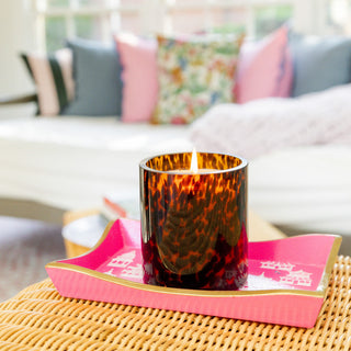 Lit Bridgewater tortoiseshell glass candle on pink decorative tray in styled living room setting.