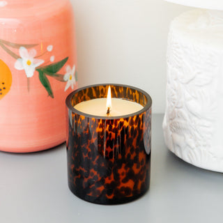 Lit Bridgewater candle in tortoiseshell amber glass vessel styled with decorative home accessories