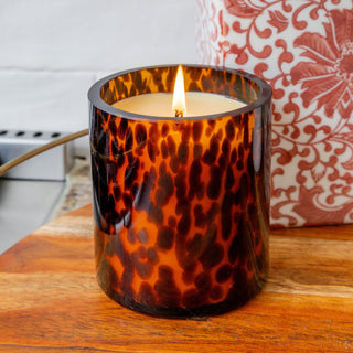Lit Bridgewater candle in tortoiseshell amber glass vessel on wooden surface