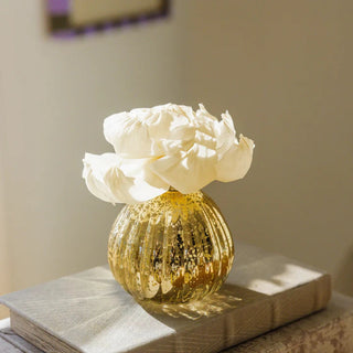 Golden mercury glass diffuser vase with vertical ribbing and speckled gold finish holding white peony