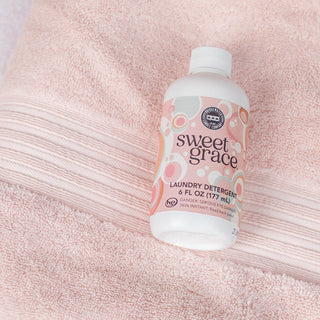 Sweet Grace laundry detergent 6 fl oz bottle by Bridgewater resting on soft pink towels