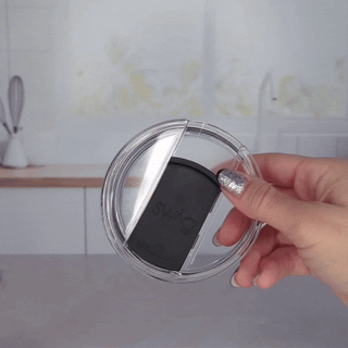 Hand holding a Swig black EZ slider lid with clear transparent rim, shown open.