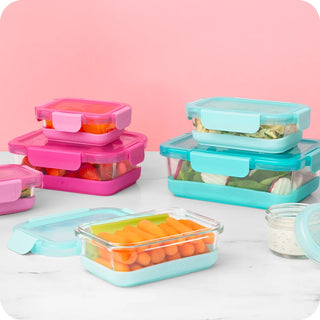 Lifestyle flat-lay of pink and turquoise glass food containers filled with fresh produce