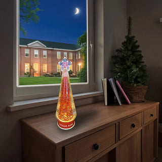 Texas A&M holiday water globe on wooden desk with warm glow and campus view
