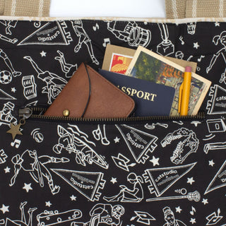 Interior zipper pocket of Catstudio collegiate tote bag holding passport, wallet, postcards, and pencil