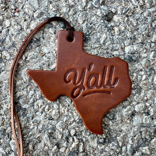 Brown leather Texas-shaped ornament with cursive Y'all engraving and leather cord