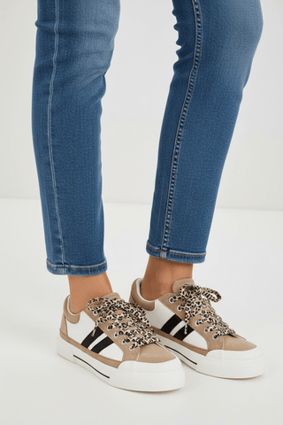 Corky's sand, white, and black sneakers with leopard print laces worn with blue jeans
