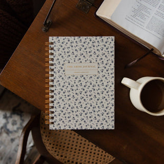 The Abide Study Journal by The Daily Grace Co, floral spiral notebook on wooden table
