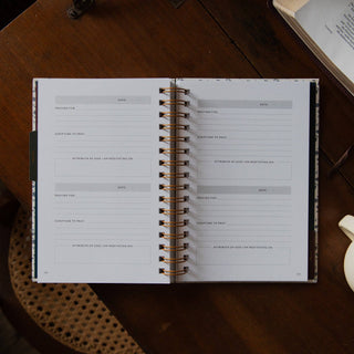 Open spiral-bound Abide Study Journal showing prayer and scripture entry pages on wood table