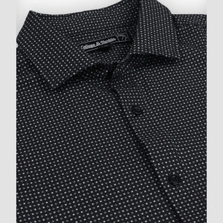 Close-up of a black patterned shirt with a collar and buttons, featuring a brand label.