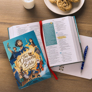 The Discovery Bible hardcover open to Psalms 22-24, displayed on wooden table with cookies and notepad