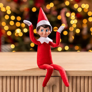 Poseable Elf on the Shelf doll in red suit sitting on shelf with Christmas tree bokeh