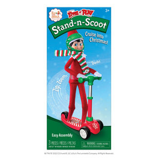Elf on the Shelf Stand-N-Scoot toy packaging showing elf riding red scooter with green accents