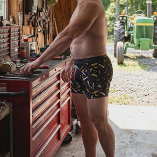 Male model wearing Shinesty Tool Belt Hammer and Tools print boxer brief underwear in garage workshop setting