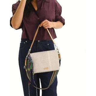 Person holding a beige handbag with a colorful strap