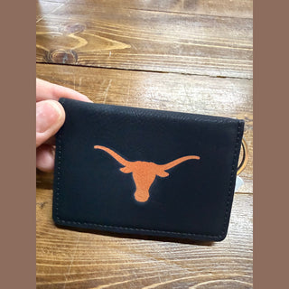 Hand holding slim navy leather Longhorn ID case demonstrating portability and logo contrast