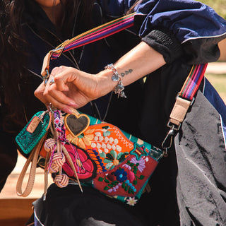 Woman holding Consuela Uptown Crossbody in Marlow, a colorful embroidered floral patchwork bag with rainbow strap.