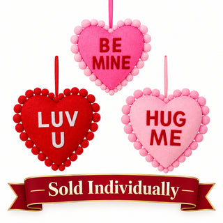 Three velvet pompom-trimmed conversation hearts in red and pink with LUV U, BE MINE, HUG ME