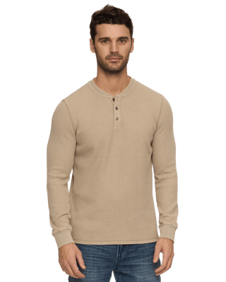 Man wearing a tan long-sleeve waffle knit henley shirt with three buttons and blue jeans