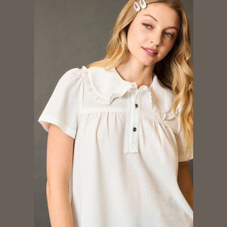 Woman wearing a white blouse with ruffled collar 