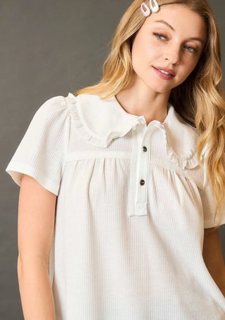 Woman wearing a white blouse with ruffled collar 