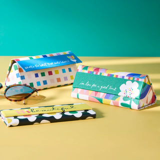 Set of four colorful collapsible sunglass cases with inspirational quotes on yellow background.