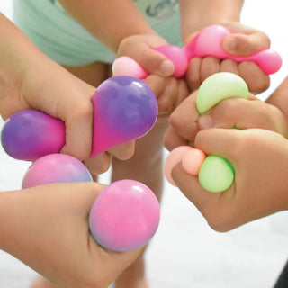 Multiple hands holding colorful Nee Doh stress balls in pink, purple, green, and gradient colors